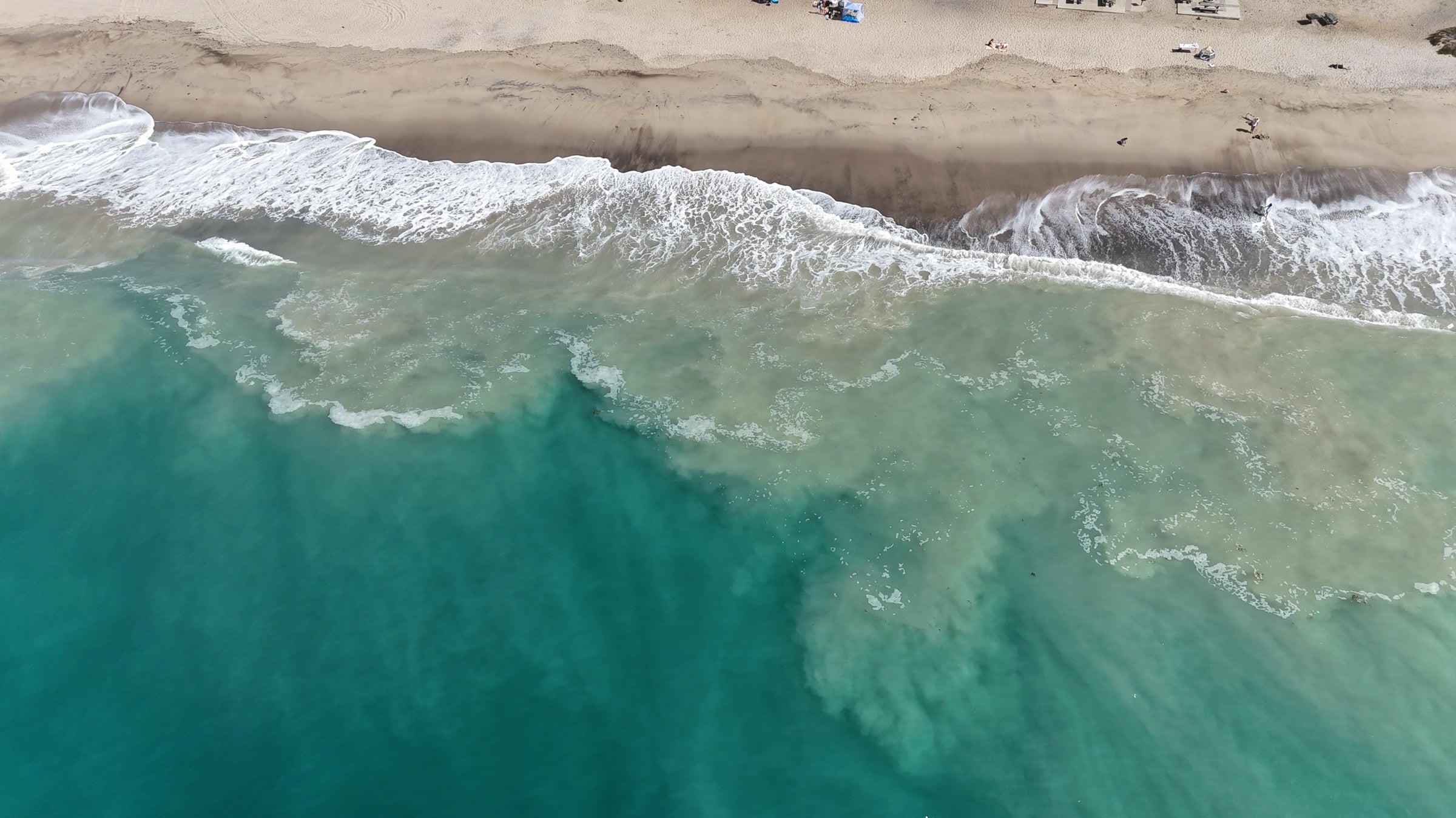 Wave foam reaching the sandy shoreline