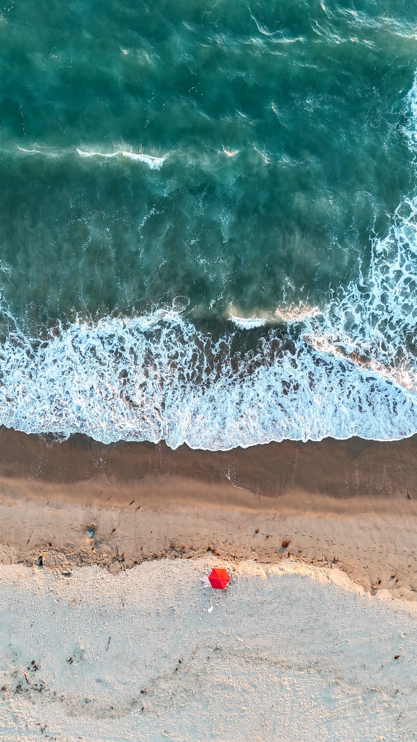 Teal Pacific surf folding onto a sandy shoreline